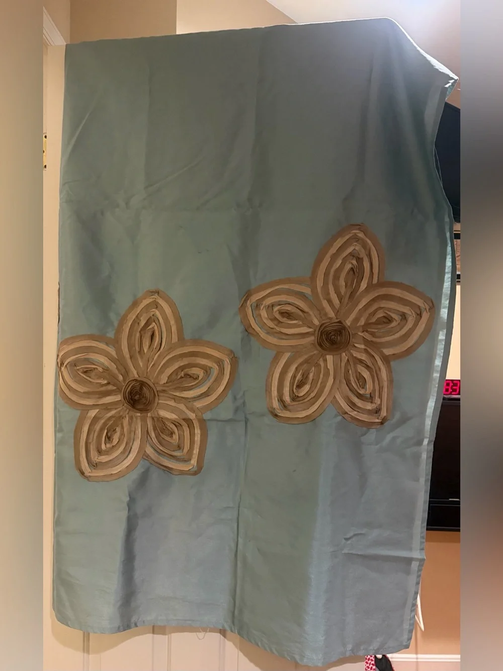 Fabric shower curtain in light teal with tan/gold flowers.